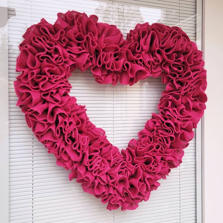 a heart shaped wreath hanging on the side of a door in front of a window