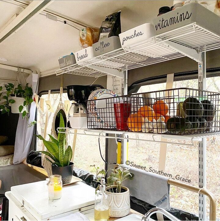 the inside of a camper with plants and other things on shelves above it,