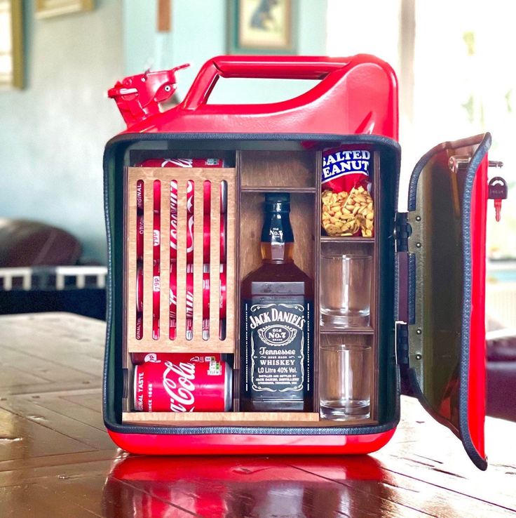 a red lunchbox with drinks and snacks in it sitting on a wooden table top