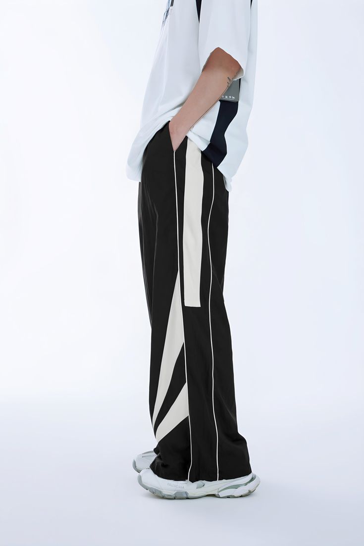 Expertly designed with a geometric pattern, these dark grey and black wide-leg pants feature side stripes for a bold look. Made with a cotton blend fabric and nylon composition, the loose fit provides comfort and style. Available in sizes S-XL for men. Trendy Wide Leg Pants With Contrast Color, Black Straight Leg Bottoms With Contrast Color, Black Cotton Pants With Contrast Color, Black Pants With Contrast Stripes For Streetwear, Black Wide-leg Pants With Contrast Stripes, Wide Leg Cotton Pants With Contrast Stripes, Black Wide Leg Pants With Contrast Stripes, Black Trousers With Contrast Stripes, Sporty Wide Leg Pants For Streetwear