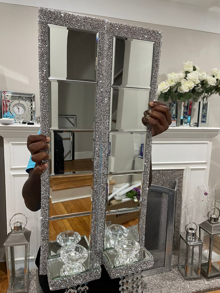 a woman holding up a large mirror in front of her face with flowers on it