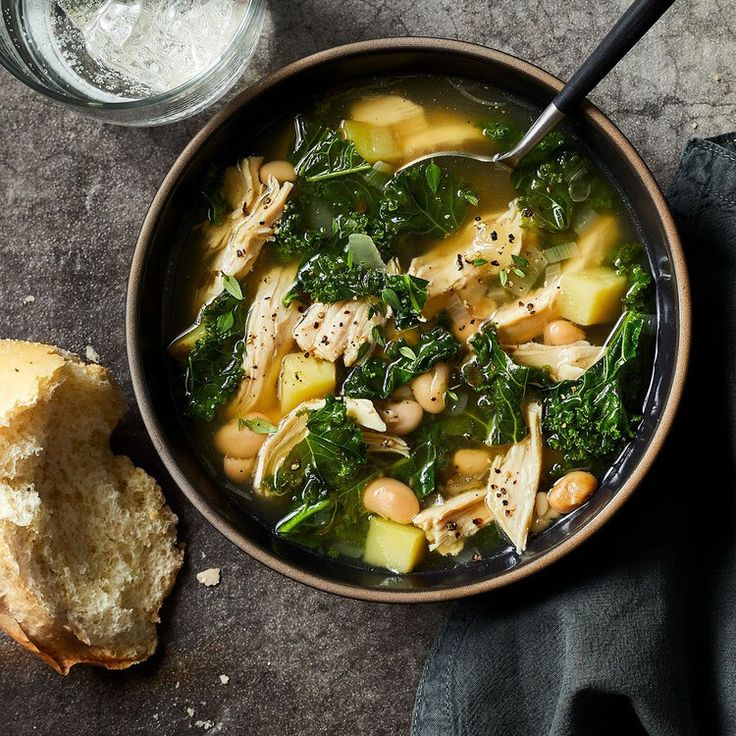 a bowl filled with soup next to a piece of bread on top of a table