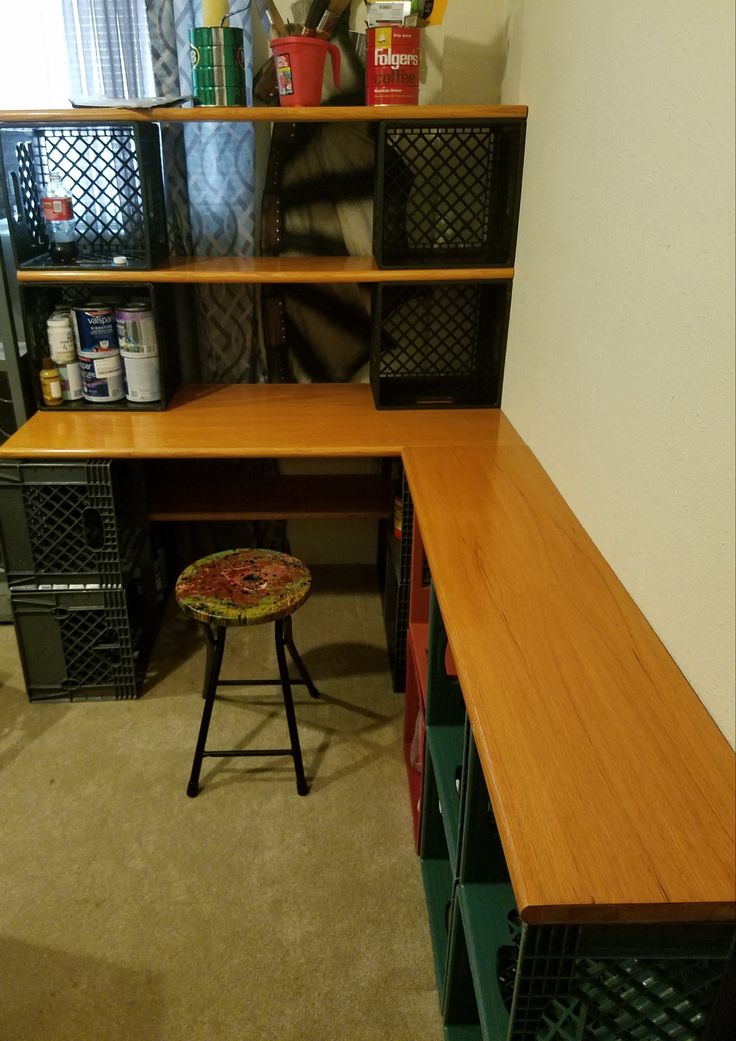 a wooden desk sitting in the corner of a room with lots of storage containers on it