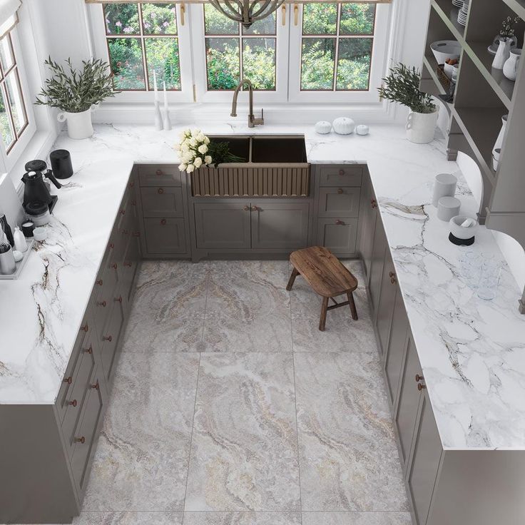 a kitchen with white marble counter tops and gray cabinets, along with a wooden stool