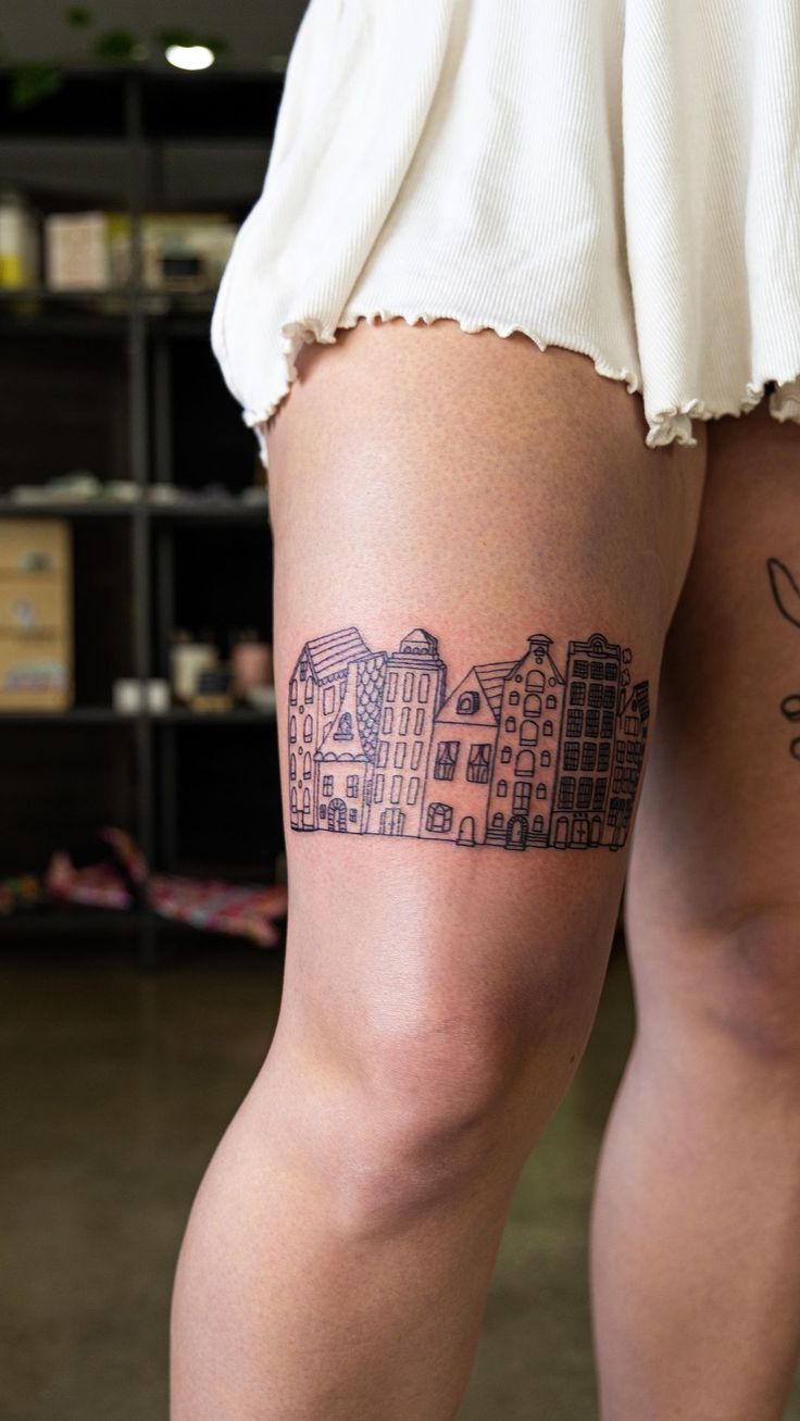 a woman's legs with tattoos on them, and buildings in the back ground