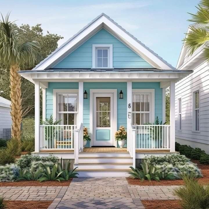 a blue and white house with palm trees in the front yard