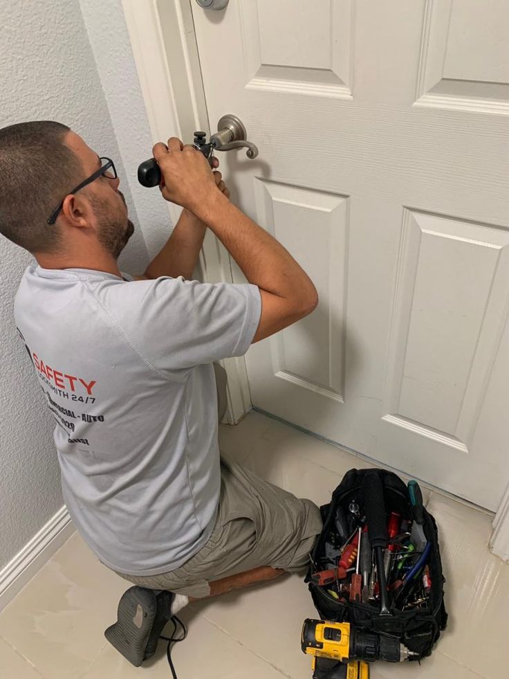 a man working on a door handle with tools in front of him and his tool bag