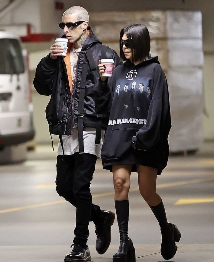 two people walking down the street holding coffee