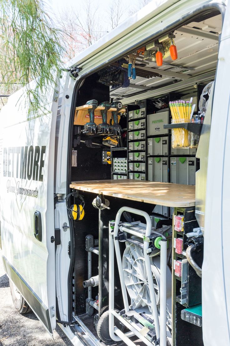 the back end of a van with its doors open and shelves full of items in it