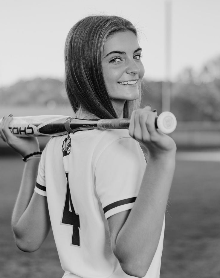 a woman is holding a baseball bat and smiling