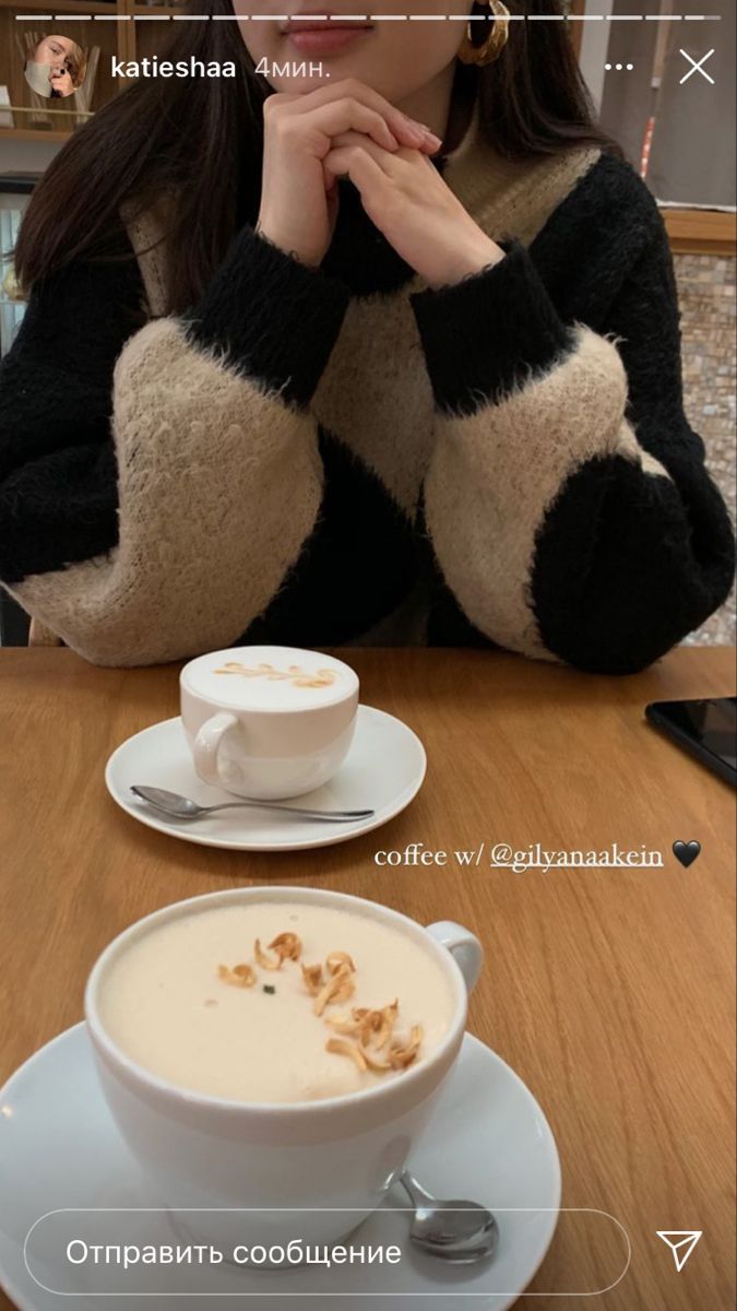 a woman sitting at a table in front of a cup of cappuccino