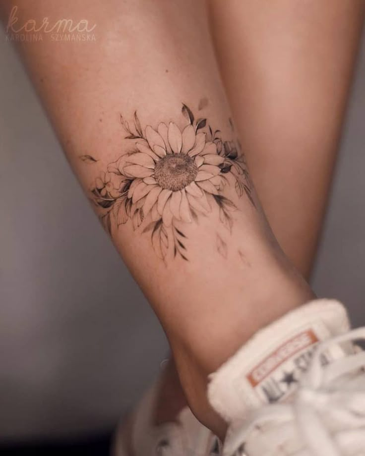 a woman's foot with a sunflower tattoo on it