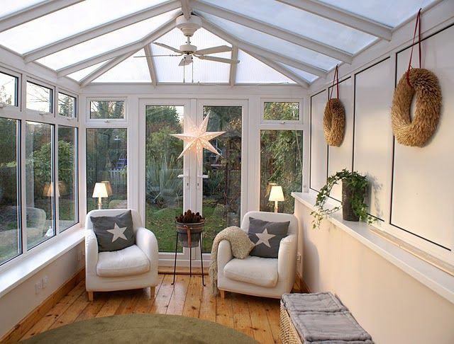 two white chairs sitting in a sun room