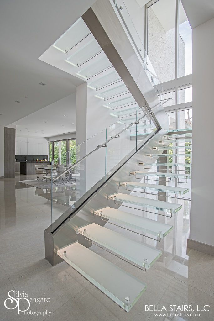 a glass staircase in a modern home with stainless steel handrails and white tile flooring