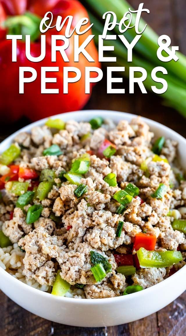 a white bowl filled with tuna and peppers on top of a wooden table next to green beans