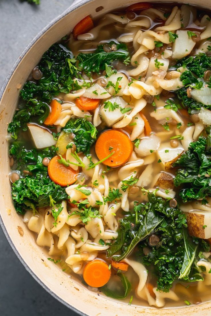 a pot filled with noodles, carrots and broccoli