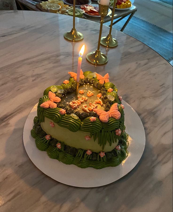 a birthday cake sitting on top of a table with lit candles in the shape of a heart