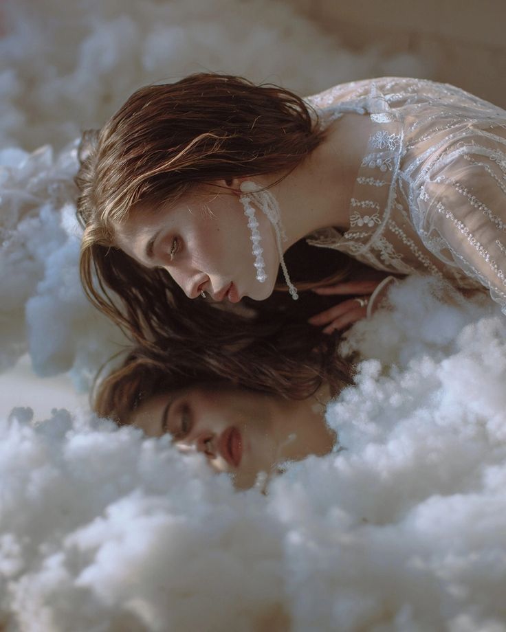 two women laying on top of white fluffy clouds