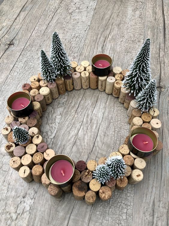 a wreath made out of wine corks with candles and pine cones on top, sitting on a wooden table