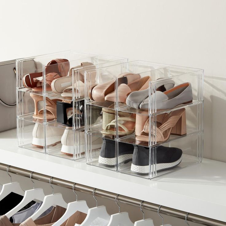 several pairs of shoes are stored in clear acrylic bins on a shelf