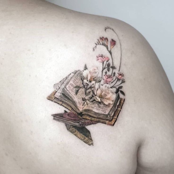 the back of a woman's shoulder with an open book and flowers on it