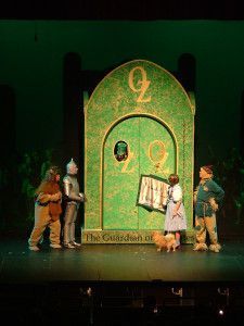 children dressed in costumes stand on stage with an adult and child standing next to them