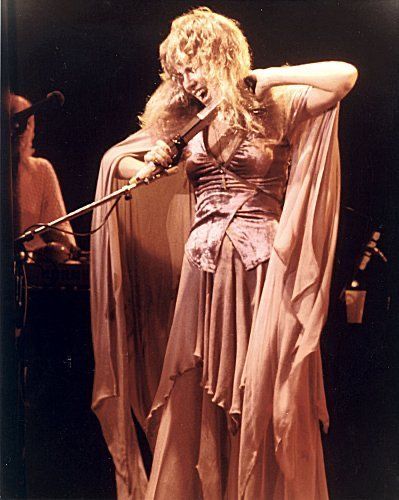 a woman with long hair wearing a dress and holding a microphone