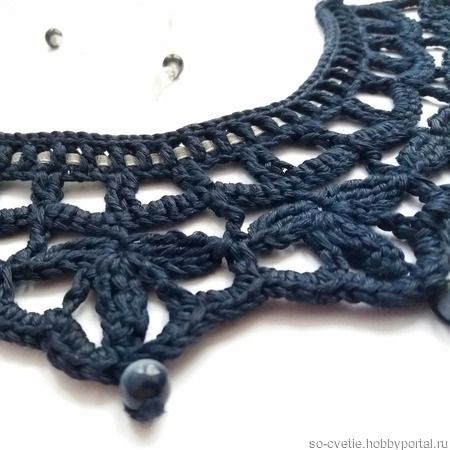 a black crochet necklace is shown on a white surface