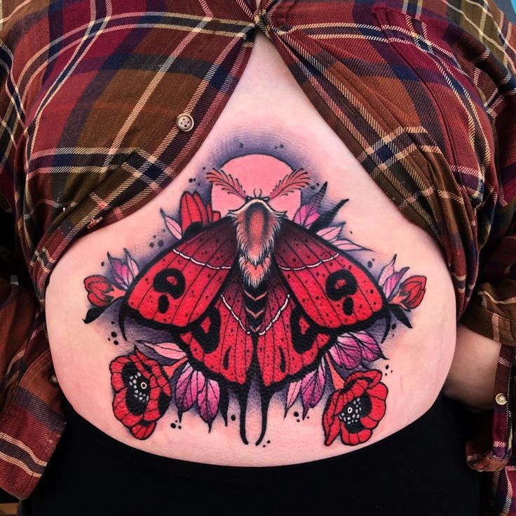 a woman's stomach with a large moth tattoo on her belly and flowers around it