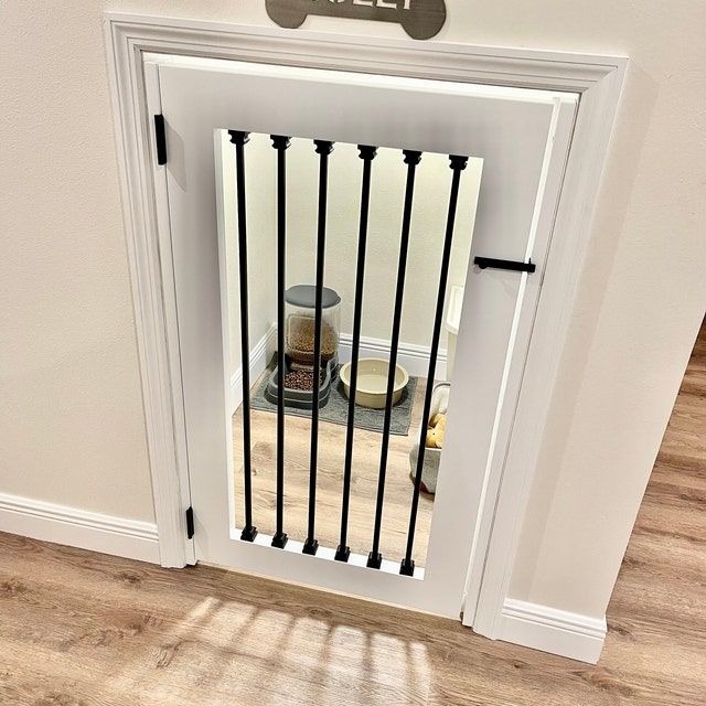 a white door with black bars and a dog bowl on the floor next to it