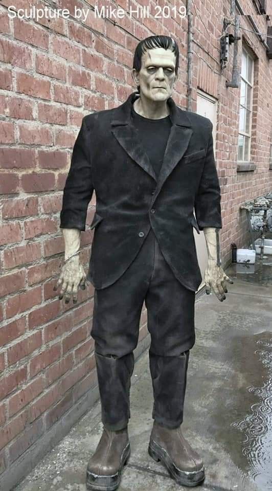 a statue of a man standing next to a brick wall