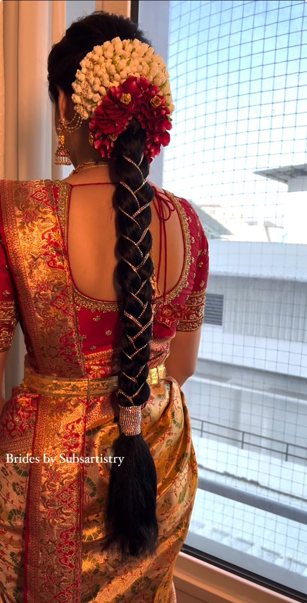 a woman with long braids and flowers in her hair is looking out the window