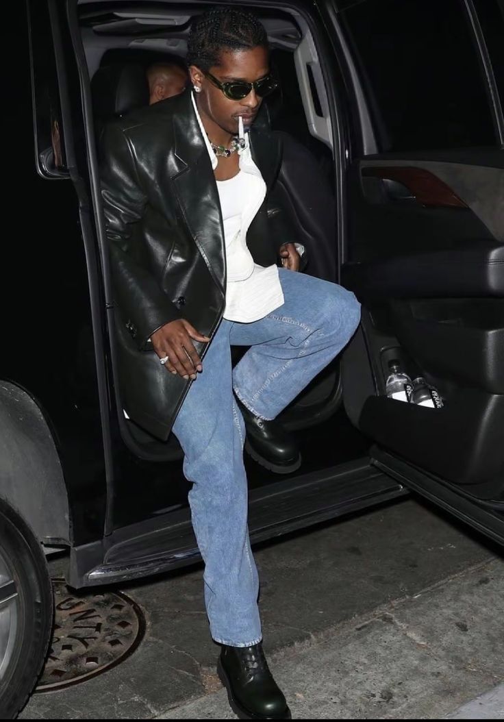 a man in black jacket and jeans stepping out of a car