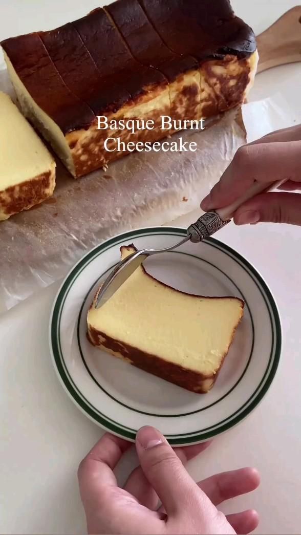 someone cutting into a piece of cheesecake on a plate