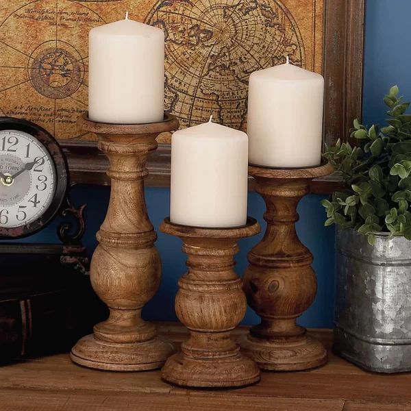 three white candles sitting on top of a wooden table