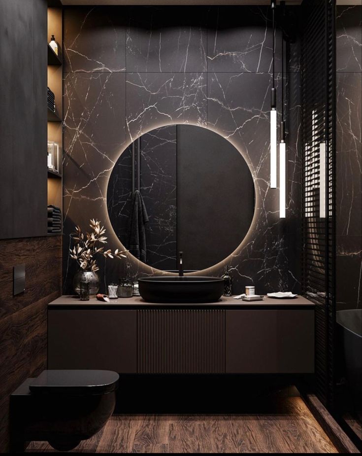 a black and white bathroom with a round mirror on the wall next to a sink