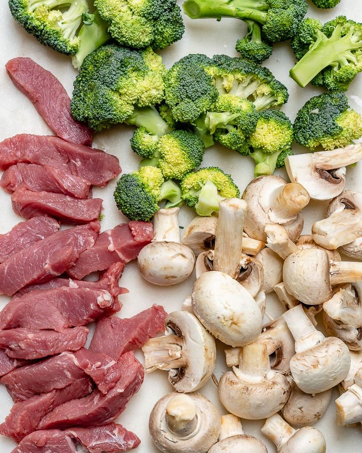 broccoli, mushrooms, and meat on a cutting board