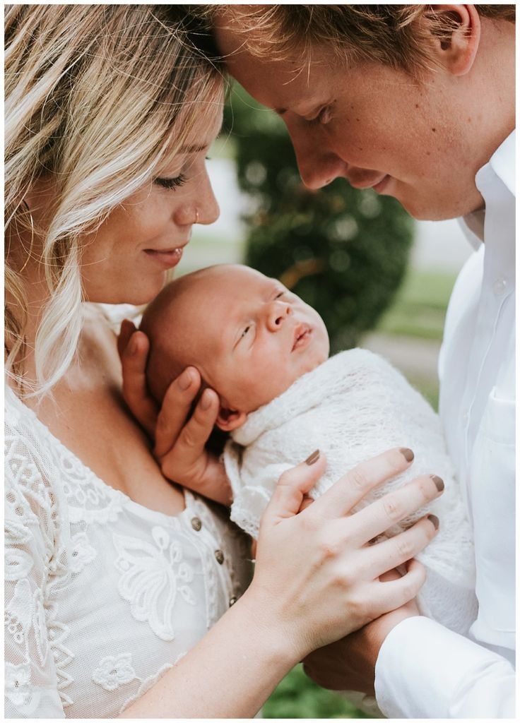 a man and woman holding a baby in their arms