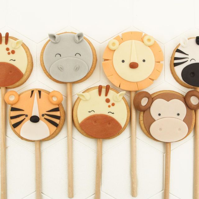 a row of decorated cookies with animal faces on them and wooden sticks in the shape of animals