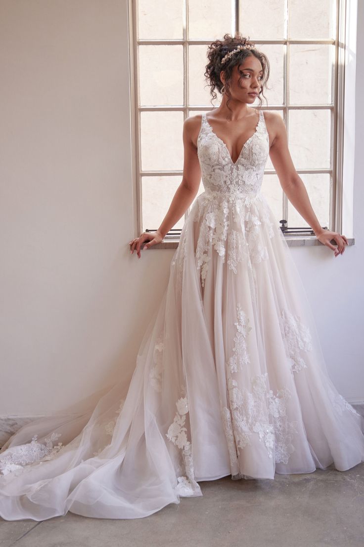 a woman standing in front of a window wearing a wedding dress