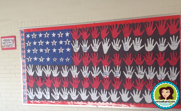 an american flag with red, white and blue hands on it hanging from the wall