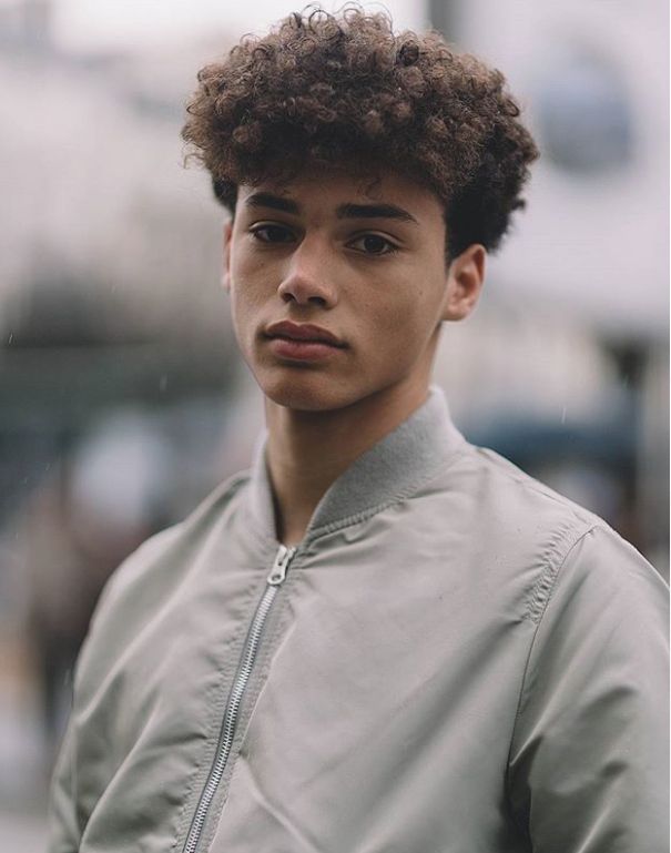 a close up of a person wearing a jacket and looking at the camera with a serious look on his face