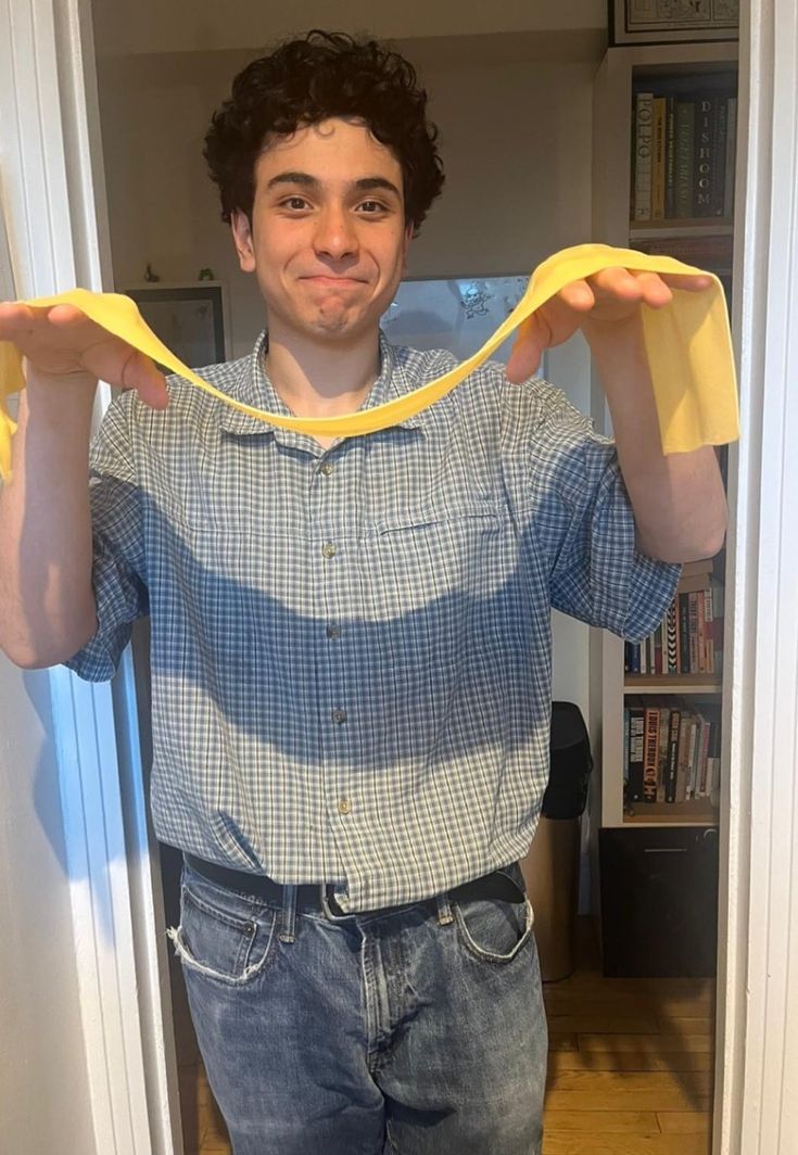 a young man holding up a banana in front of his face while standing in a doorway