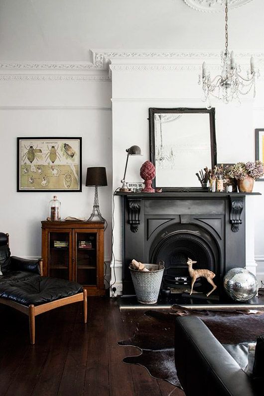 a living room filled with furniture and a fire place in front of a mirror on the wall