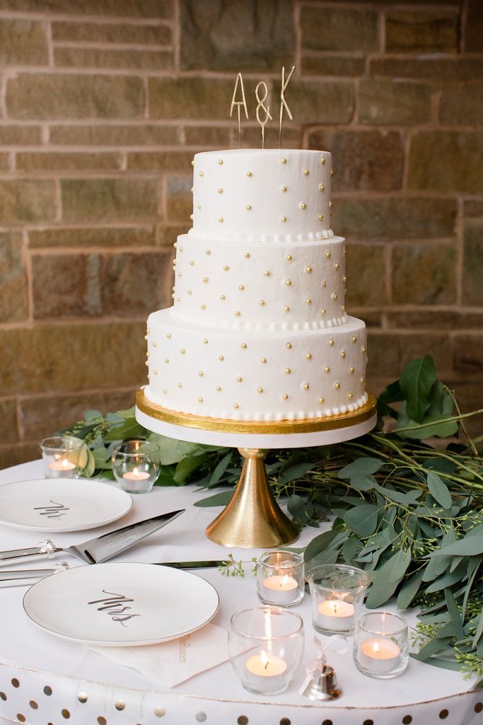 a white wedding cake sitting on top of a table next to candles and greenery