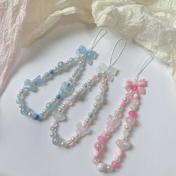 three necklaces with different colored beads and bows hanging from them on a white surface