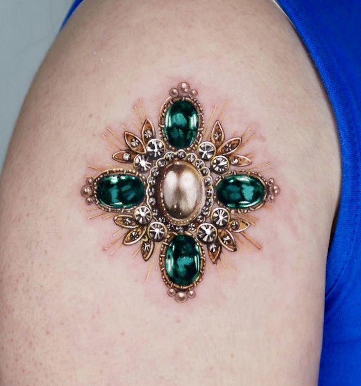 a close up of a woman's breast with green jewels and pearls on it