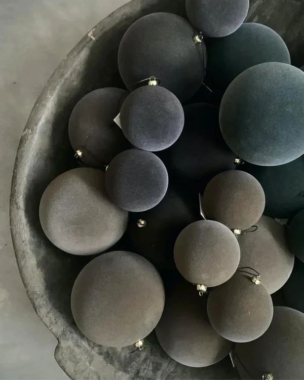 a bowl filled with lots of gray and green balls on top of a countertop