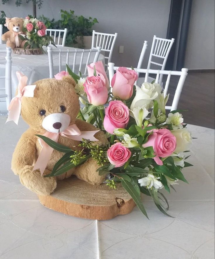 a teddy bear sitting on top of a table filled with flowers