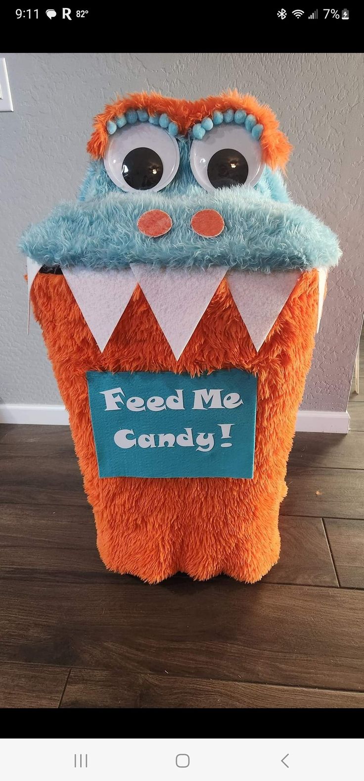 an orange stuffed animal with a sign that says feed me candy